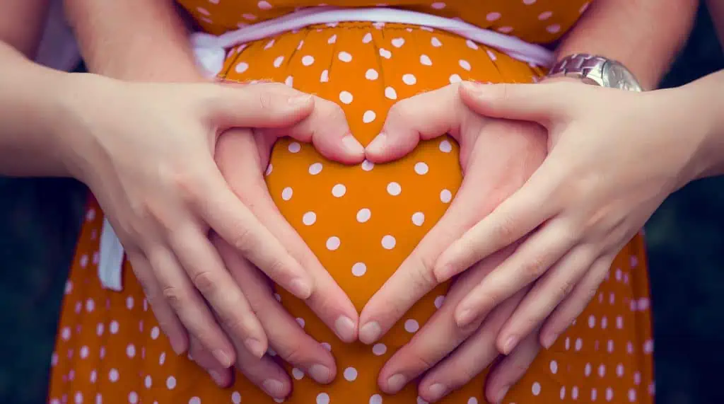 Pregnant woman with mans hand shaped as heart