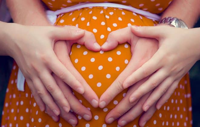 Pregnant woman with mans hand shaped as heart